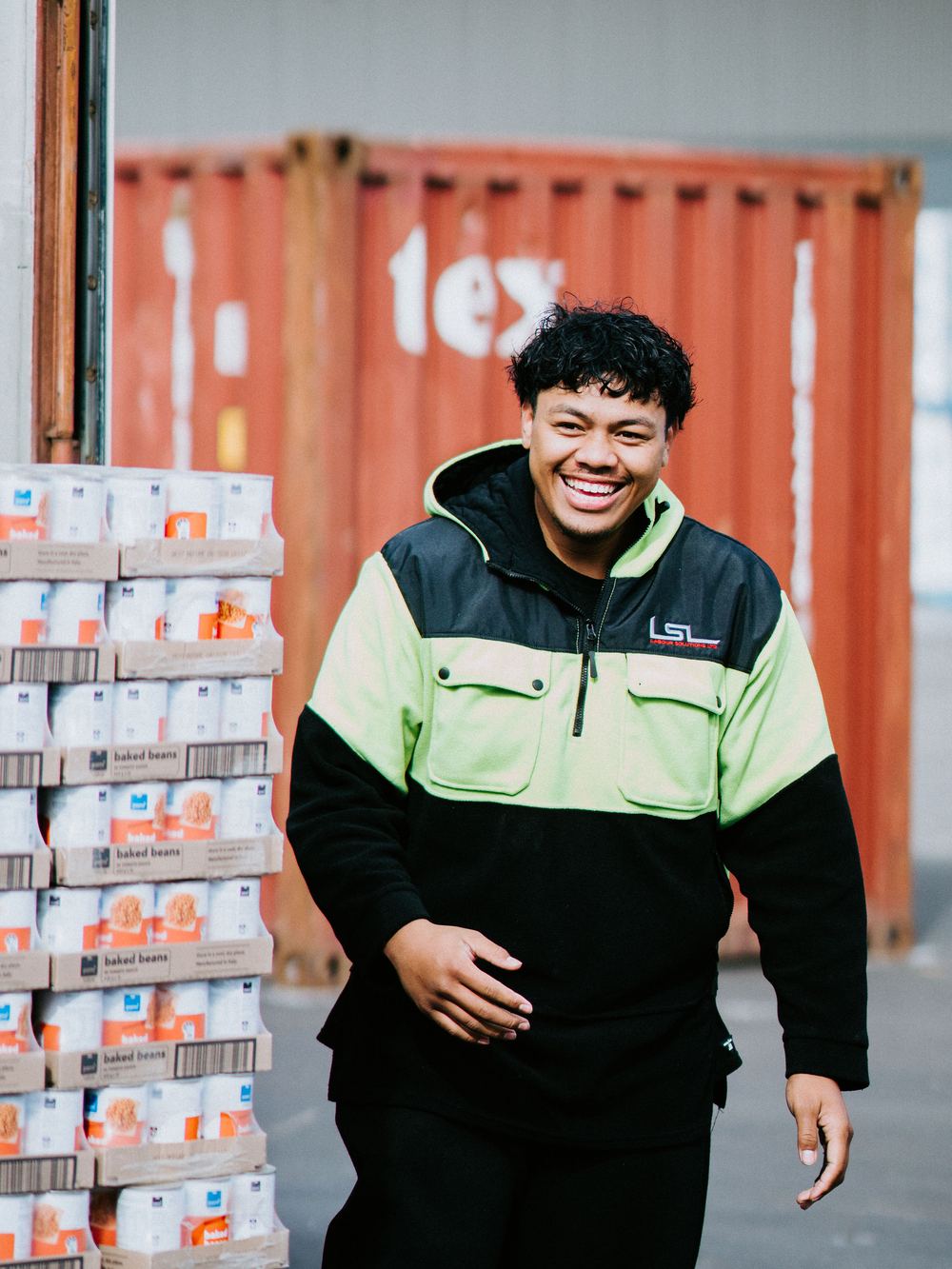 An LSL team leader walking between stacked containers