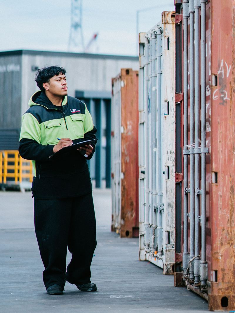 An LSL supervisor checking a worksheet beside a container